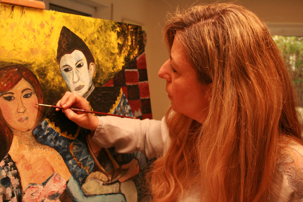 Andrea is painting with an oilpainting with 2 figures: 1 clown and 1 ballerina